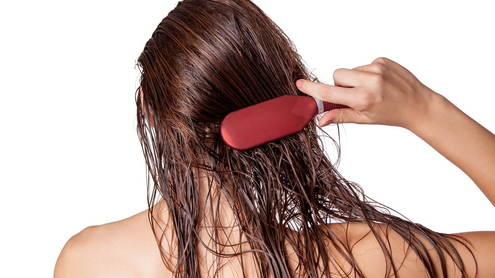 Woman with wet brown hair brushing the back of her head