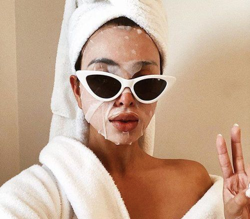 woman wearing white glasses, a face rejuvenation mask, and a white hair towel